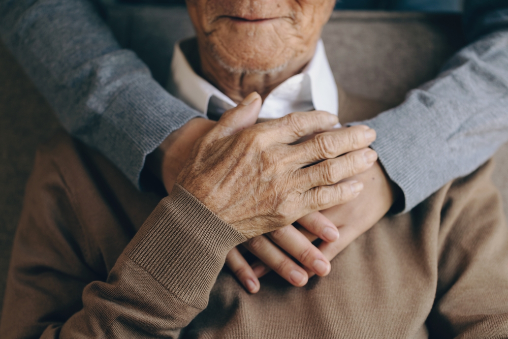 Elder man getting hugged by a healthcare worker